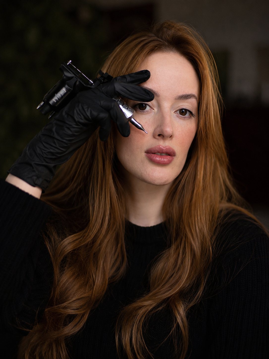 Carolina Lamarão segurando a máquina de tatuagem com luva preta